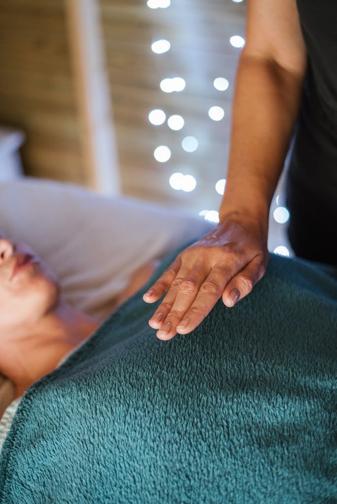 Anonymous adult female in towel having massage on comfortable couch in spa salon